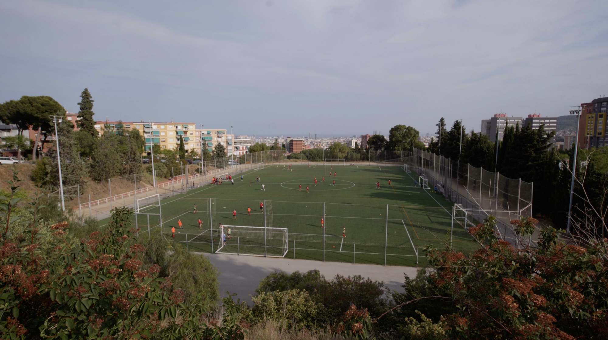 Vista del campo de fútbol de Brafa, con varios partidos y la ciudad al fondo.