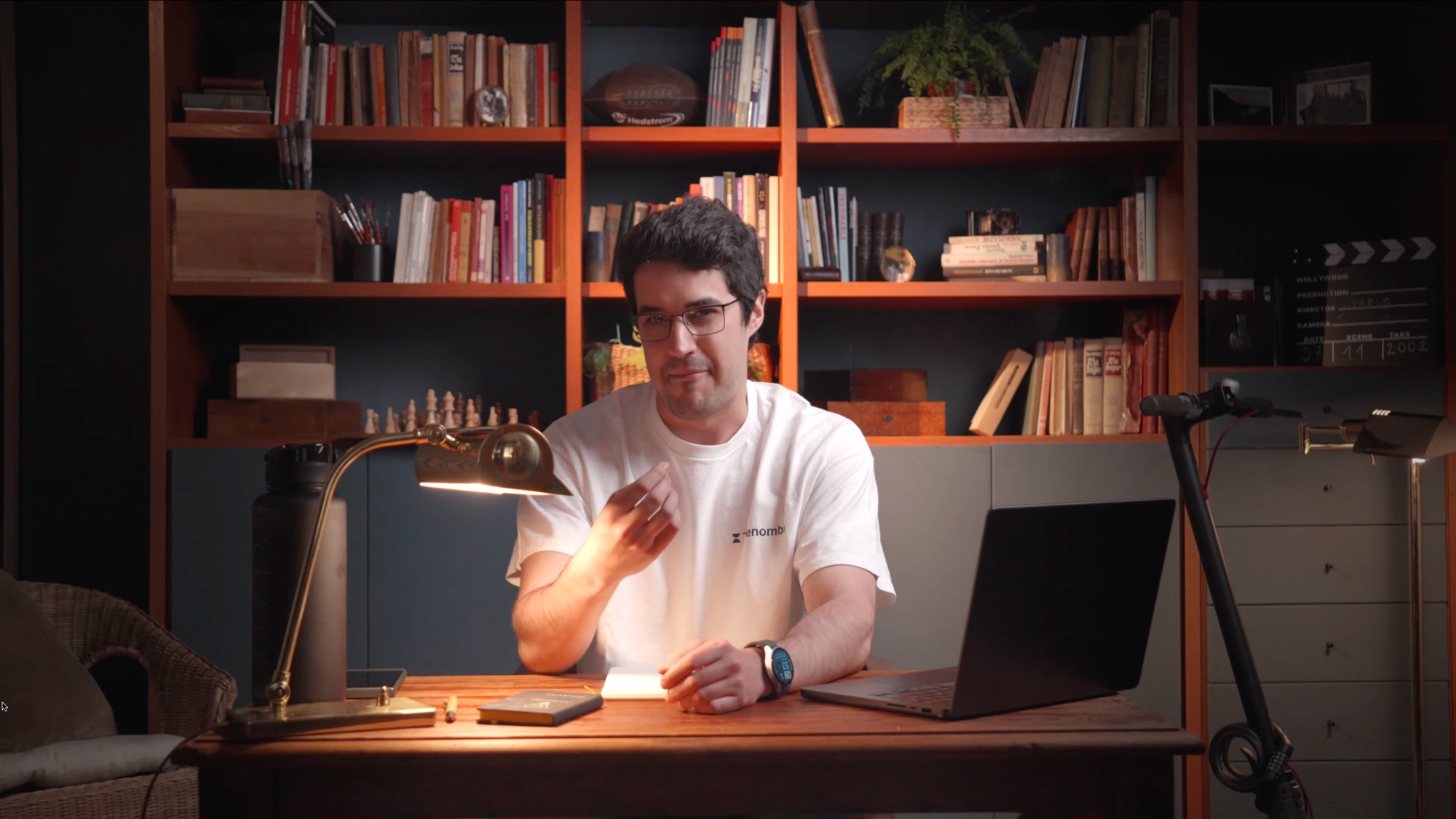 Un participante presenta una clase desde un escritorio iluminado, rodeado de libros y objetos.