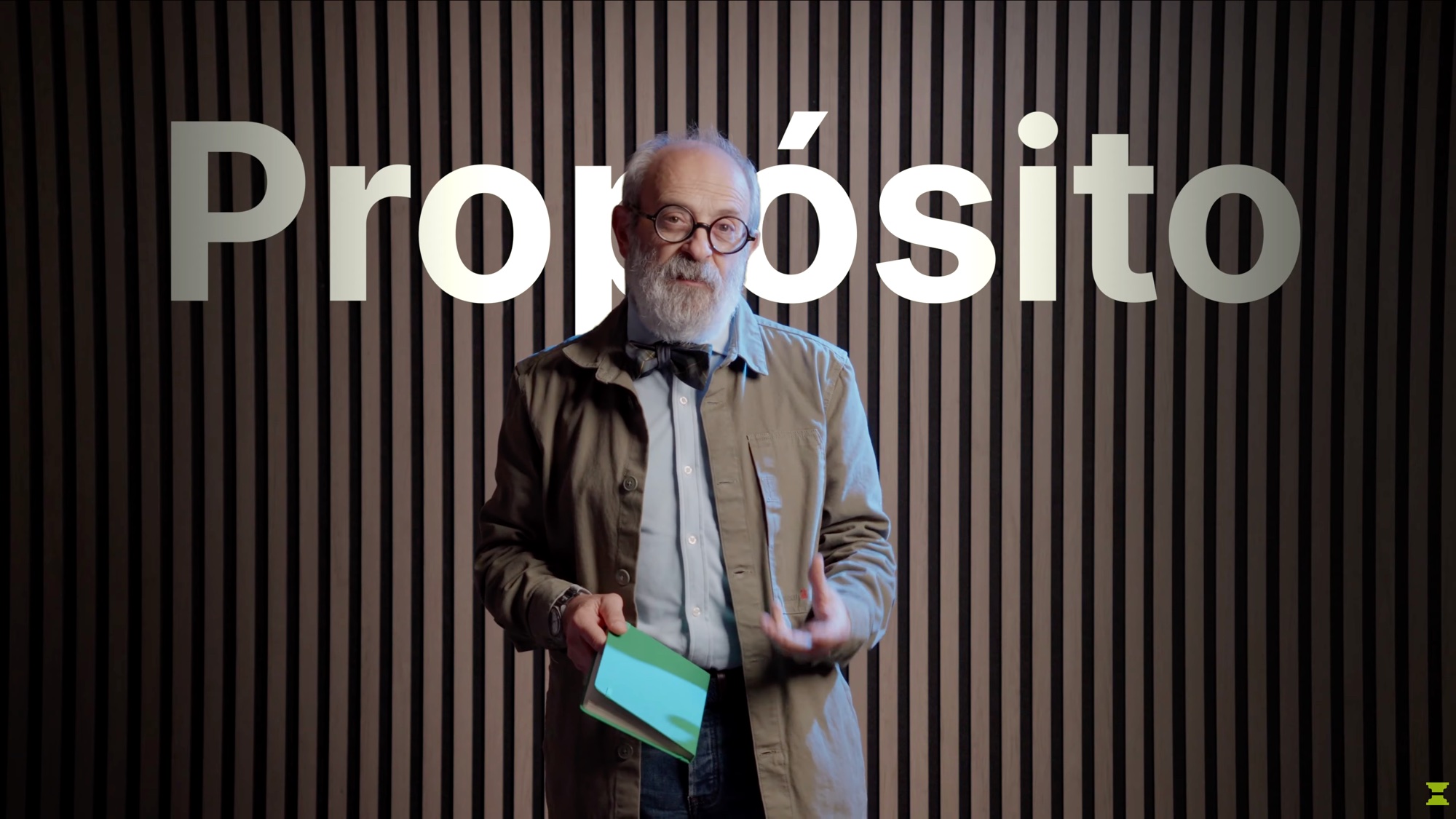 Un participante sostiene un libro ante un fondo de madera y la palabra Propósito.